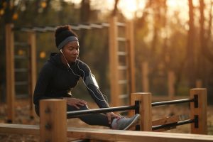 Mulher negra se exercitando ao ar livre em equipamento de madeira